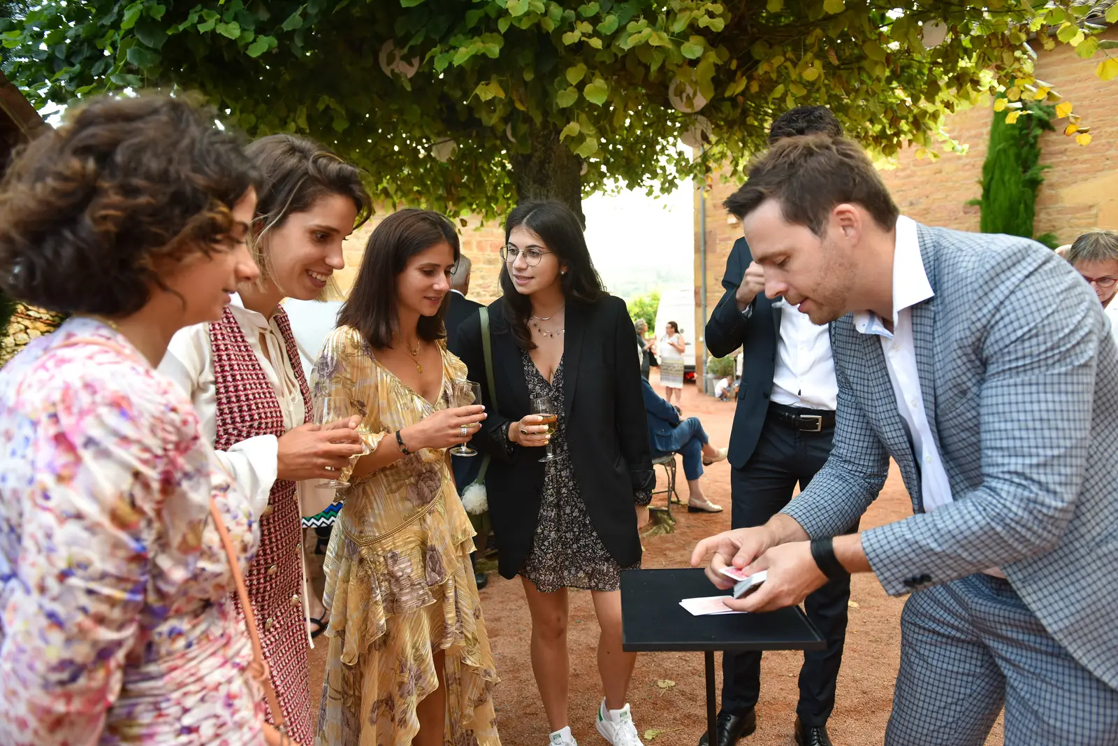 Hugo Marceau performing close-up magic for a group of wedding guests in a courtyard