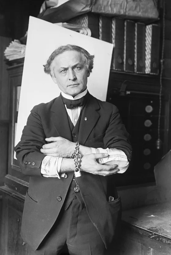 Harry Houdini menotté, photographie de 1918 — pionnier de l'escapologie et de l'art de l'évasion